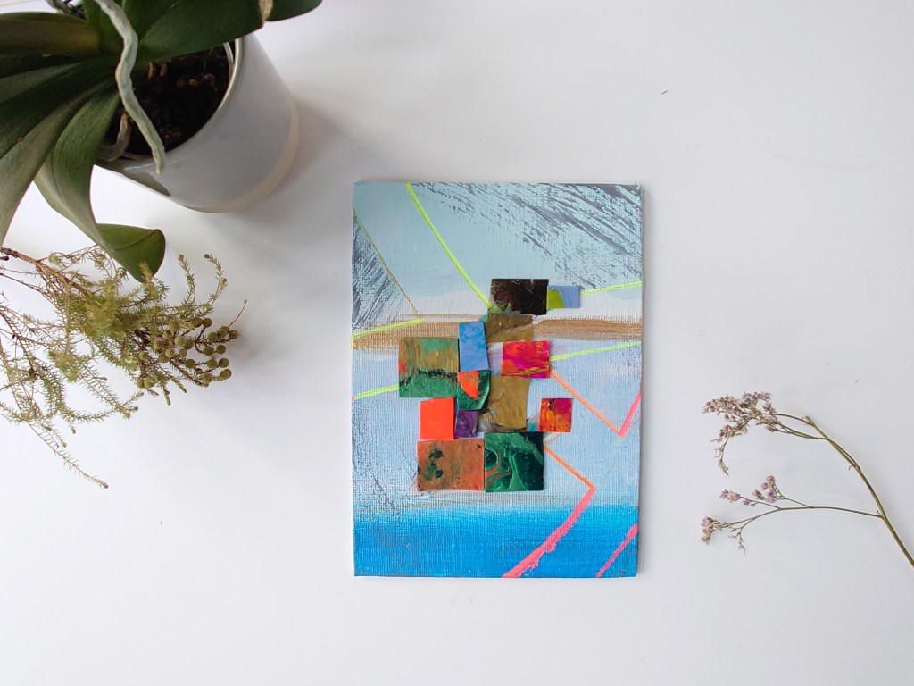 A turquoise blue and gold one of a gallery of small hand painted and crafted artwork arranged with sea lavender and other flowers for a whimsical scene. Styled to show the artwork. 