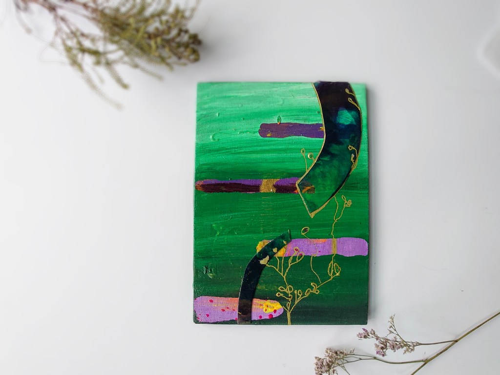 A green and lilac and deep purple one of a gallery of small hand painted and crafted artwork arranged with sea lavender and other flowers for a whimsical scene. Styled to show the artwork. 